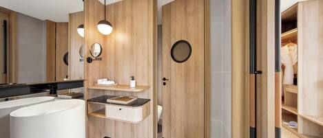 A modern bathroom with a large white sink, wooden vanity, and a round mirror.