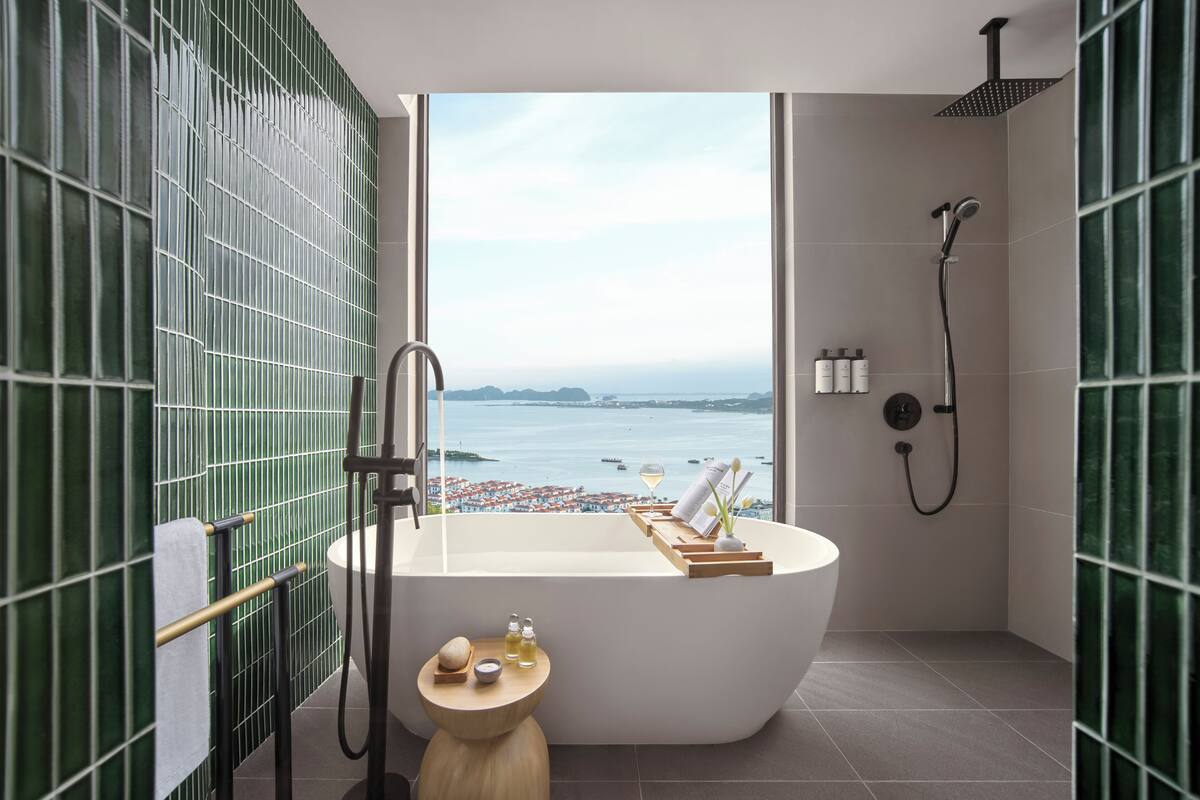 Un baño moderno con una bañera independiente, ducha y vistas al mar.