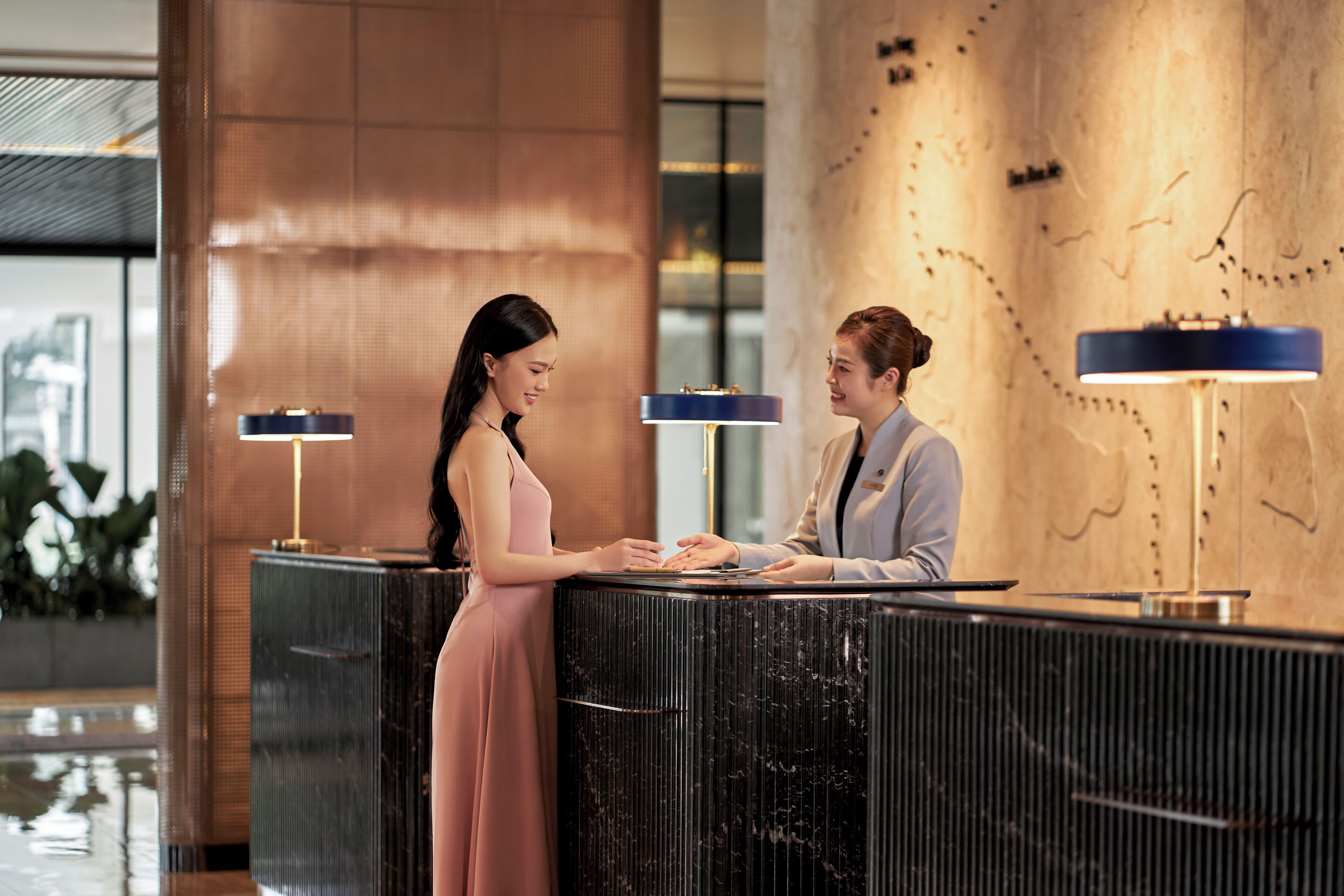 A reception area with a marble counter, two standing lamps, and a large wall with a map.