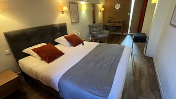 Une chambre d’hôtel avec un grand lit, un bureau, une chaise et un miroir au mur.