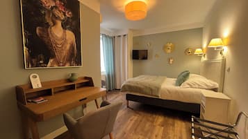 A bedroom with a bed, a desk, a chair, a TV, and decorative wall lights.