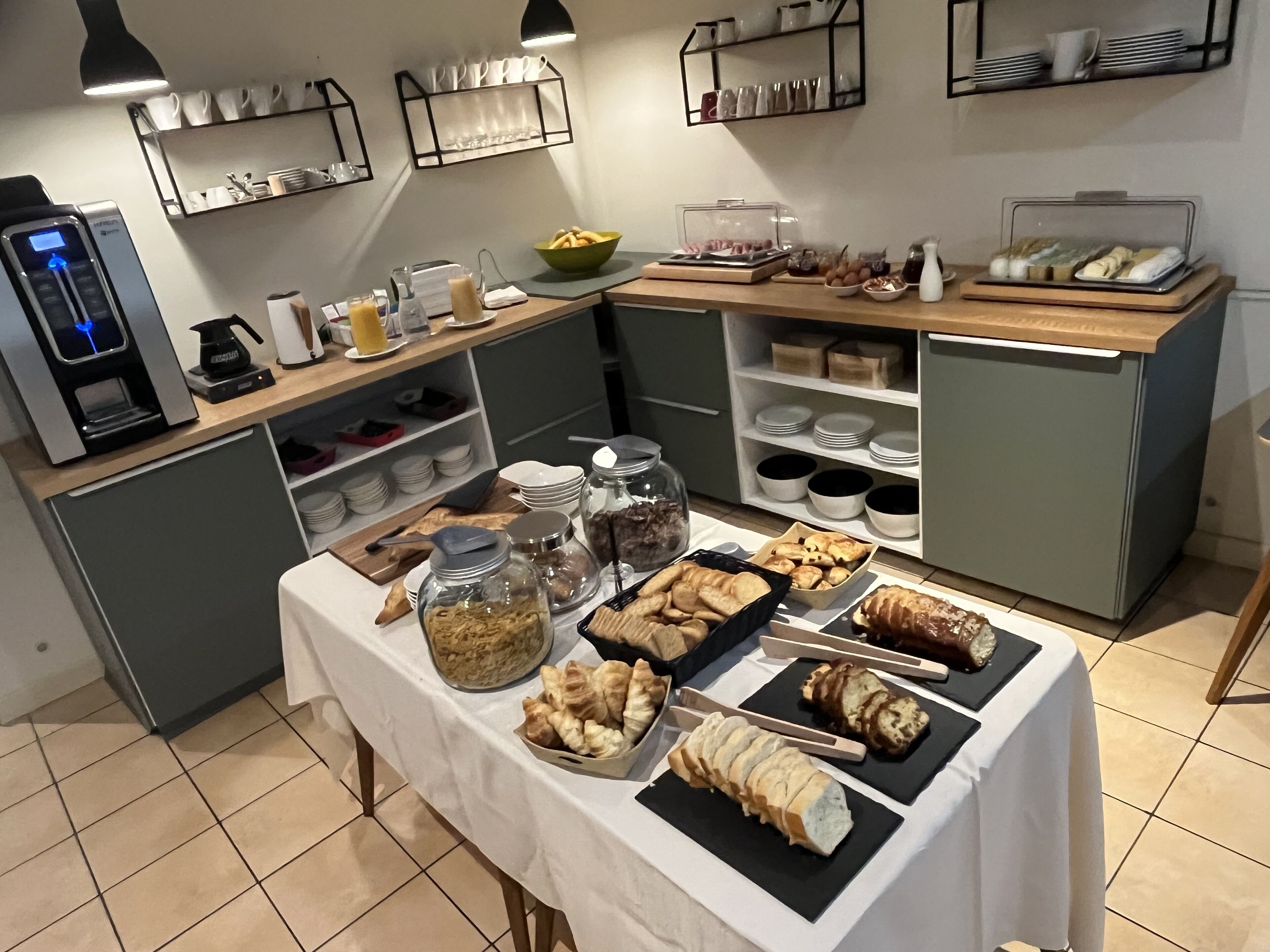 A buffet setup with various food items, a coffee machine, and storage shelves.