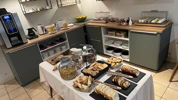 A buffet setup with various food items, a coffee machine, and storage shelves.
