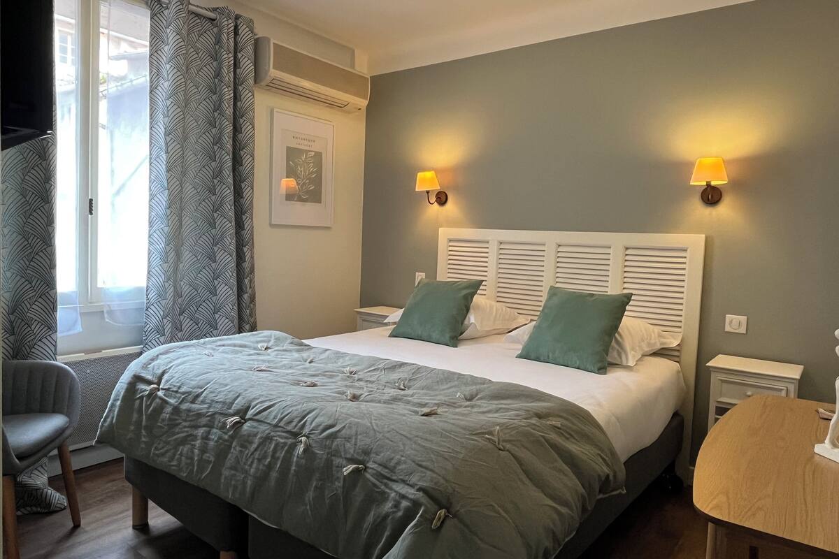 A neatly arranged bedroom with a large bed, two bedside lamps, a chair, and a small table.
