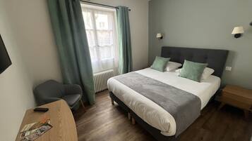 A neatly arranged bedroom with a bed, a desk, and a chair.