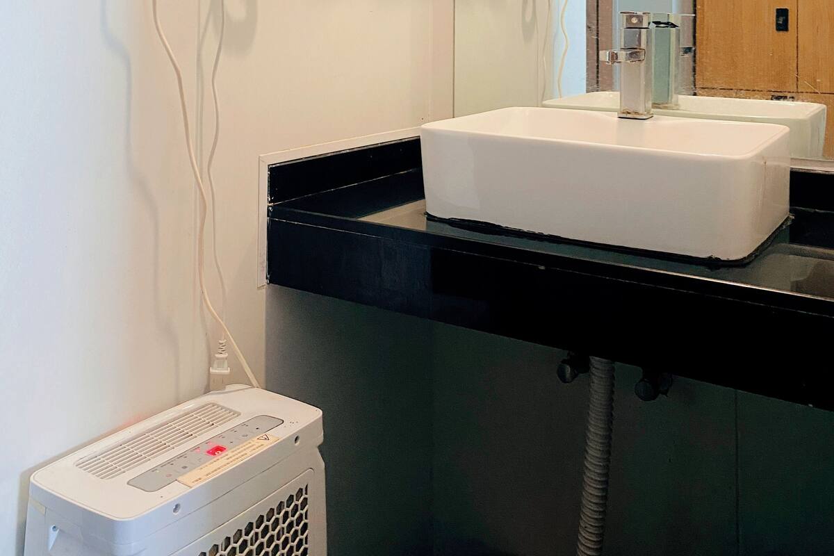 Une salle de bain avec un lavabo blanc, un sèche-cheveux et un miroir.