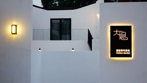 Een modern gebouw met een minimalistisch ontwerp, voorzien van een balkon en een bordje dat een verborgen tuin aangeeft.