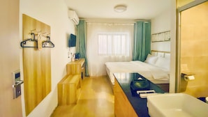 Een hotelkamer met een bed, een bureau, een stoel, een badkamer met bad en een raam met gordijnen.