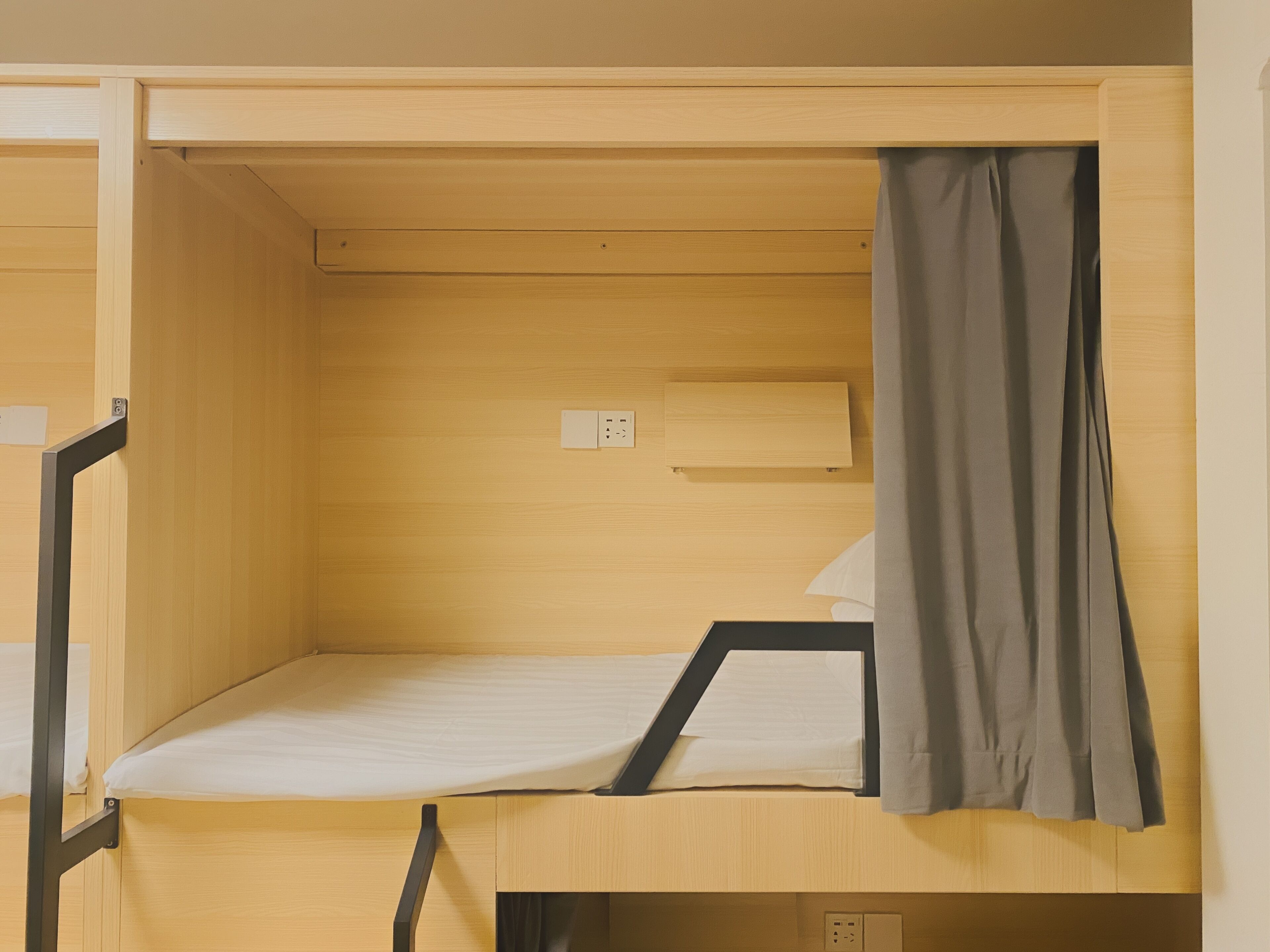 A bunk bed with a wooden frame, a small shelf, and a power outlet.
