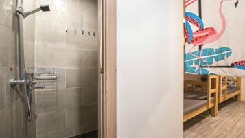 A shower with a handheld showerhead and a wall-mounted faucet.