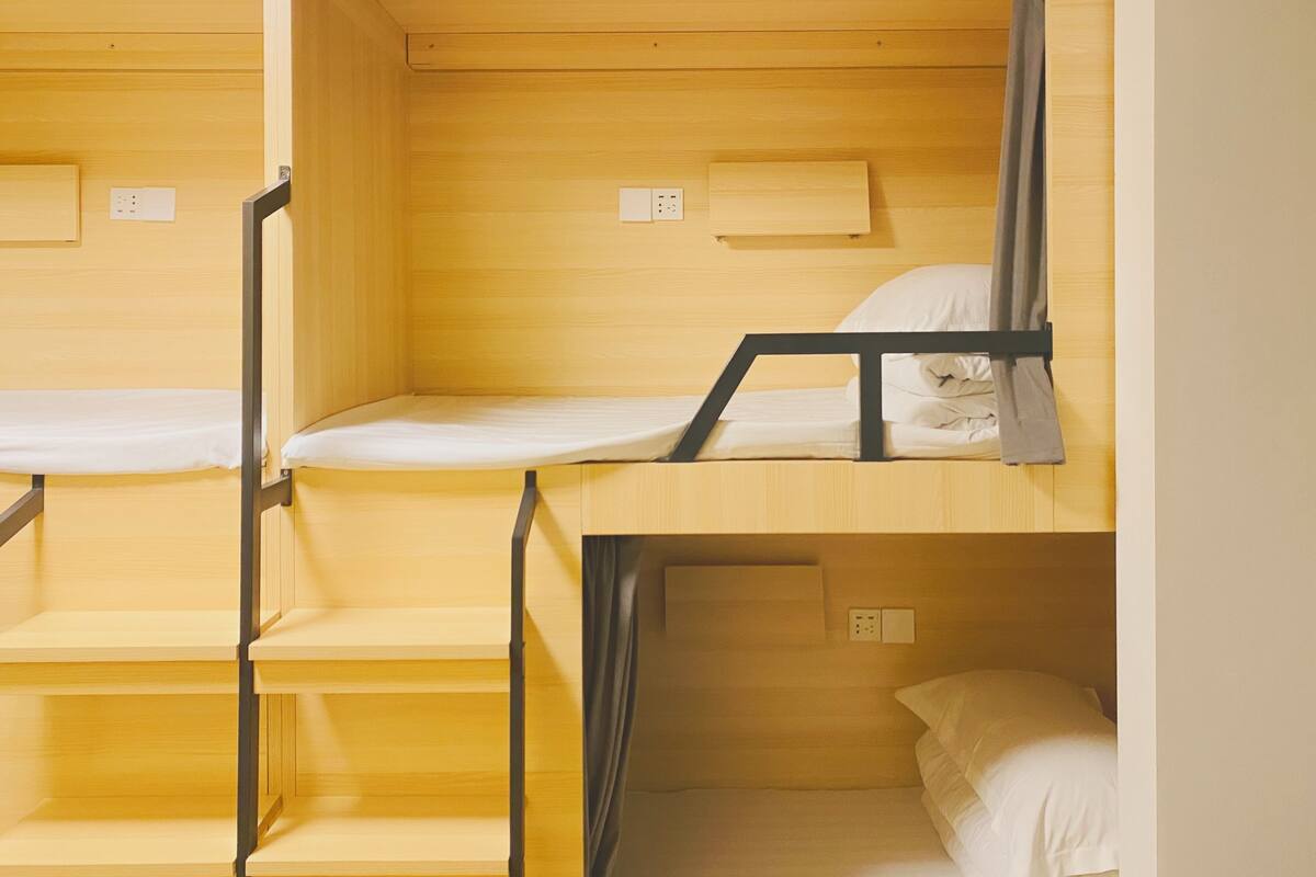 Une chambre avec des lits superposés, des murs en bois et des barreaux en métal.