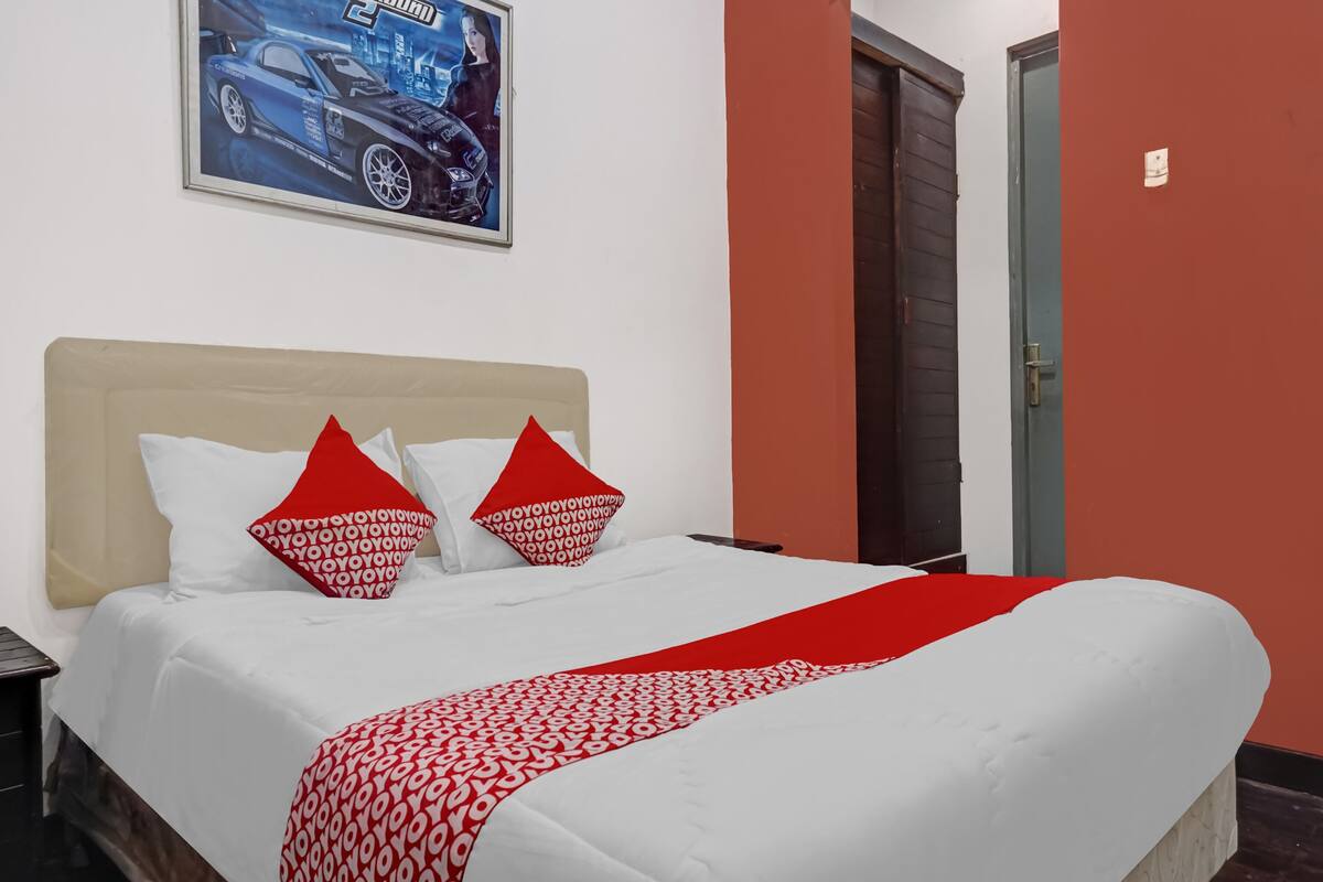 Una cama bien hecha con ropa de cama blanca y roja, un cabecero y un cartel en la pared.