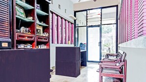 A room with a large sliding glass door leading to an outdoor area, a wooden reception desk, and a seating area with chairs. - OYO 90696 Tobana House Bintaro (Jakarta)