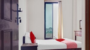A bedroom with a bed, a wooden nightstand, a mirror, and a sliding glass door leading to a balcony. - OYO 90696 Tobana House Bintaro (Jakarta)