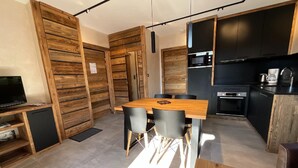 Eine moderne Küche mit schwarzen Schränken, einem Holztisch und einem Fernseher auf einem Regal.