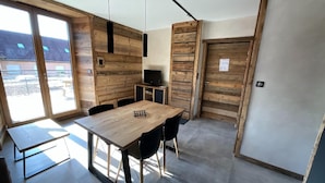 Ein modernes Interieur mit einem Holzesstisch, Stühlen, einem Fernseher und einer Schiebetür.