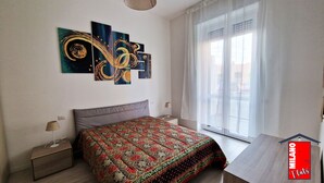 Une chambre à coucher avec un lit, une table de chevet, un bureau et une fenêtre avec des rideaux.