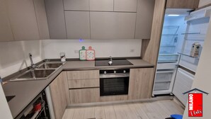 Une cuisine de taille réduite équipée d’un évier, d’une cuisinière, d’un four et d’un réfrigérateur.