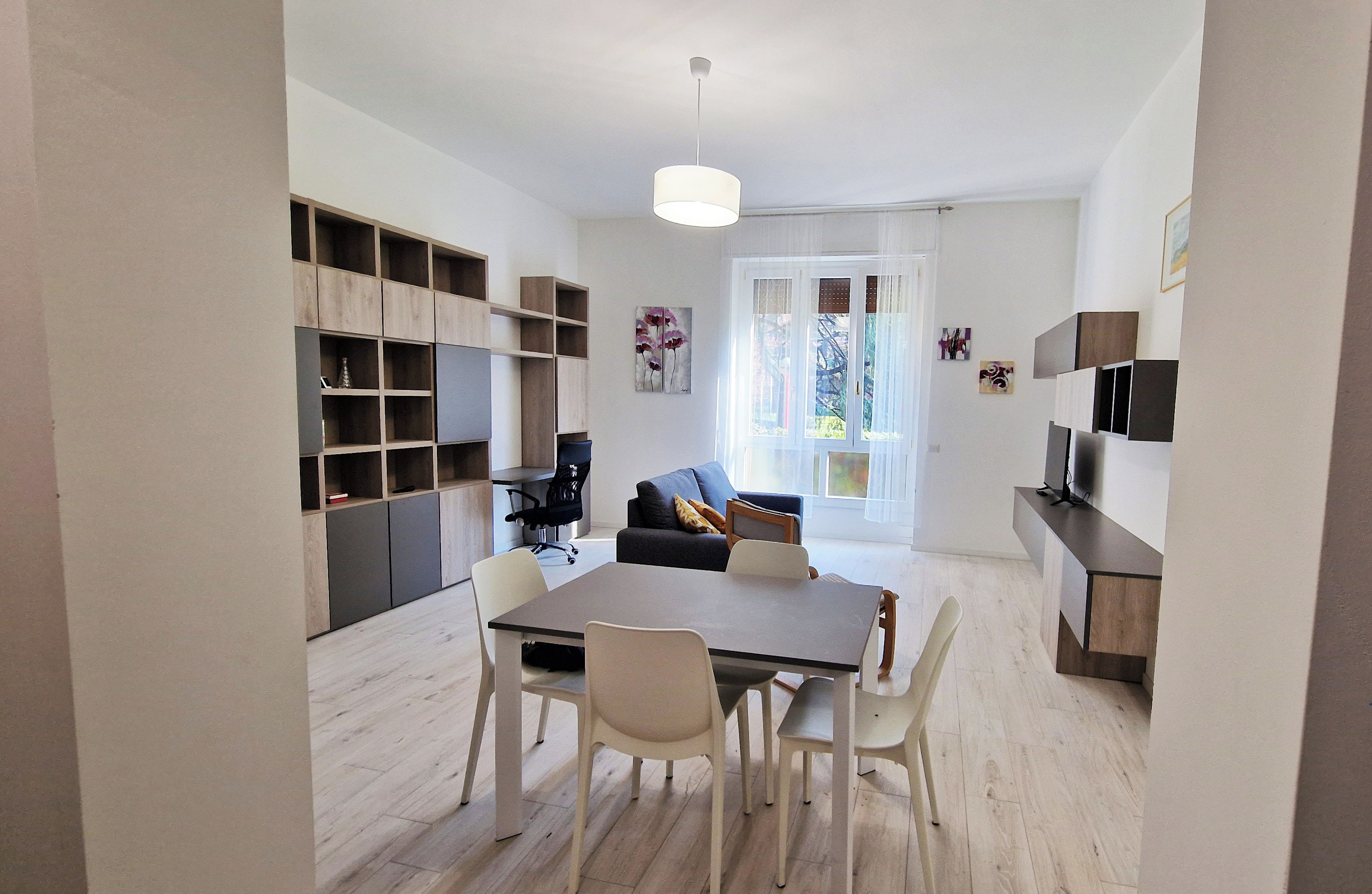A modern apartment with a dining area, a living room with a sofa, and a kitchen area.