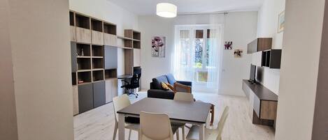 A modern apartment with a dining area, a living room with a sofa, and a kitchen area.