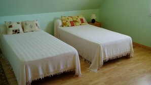 Two single beds with white bedding in a room with a wooden floor and light green walls. - Propriété (Saint-Pierre-Quiberon)