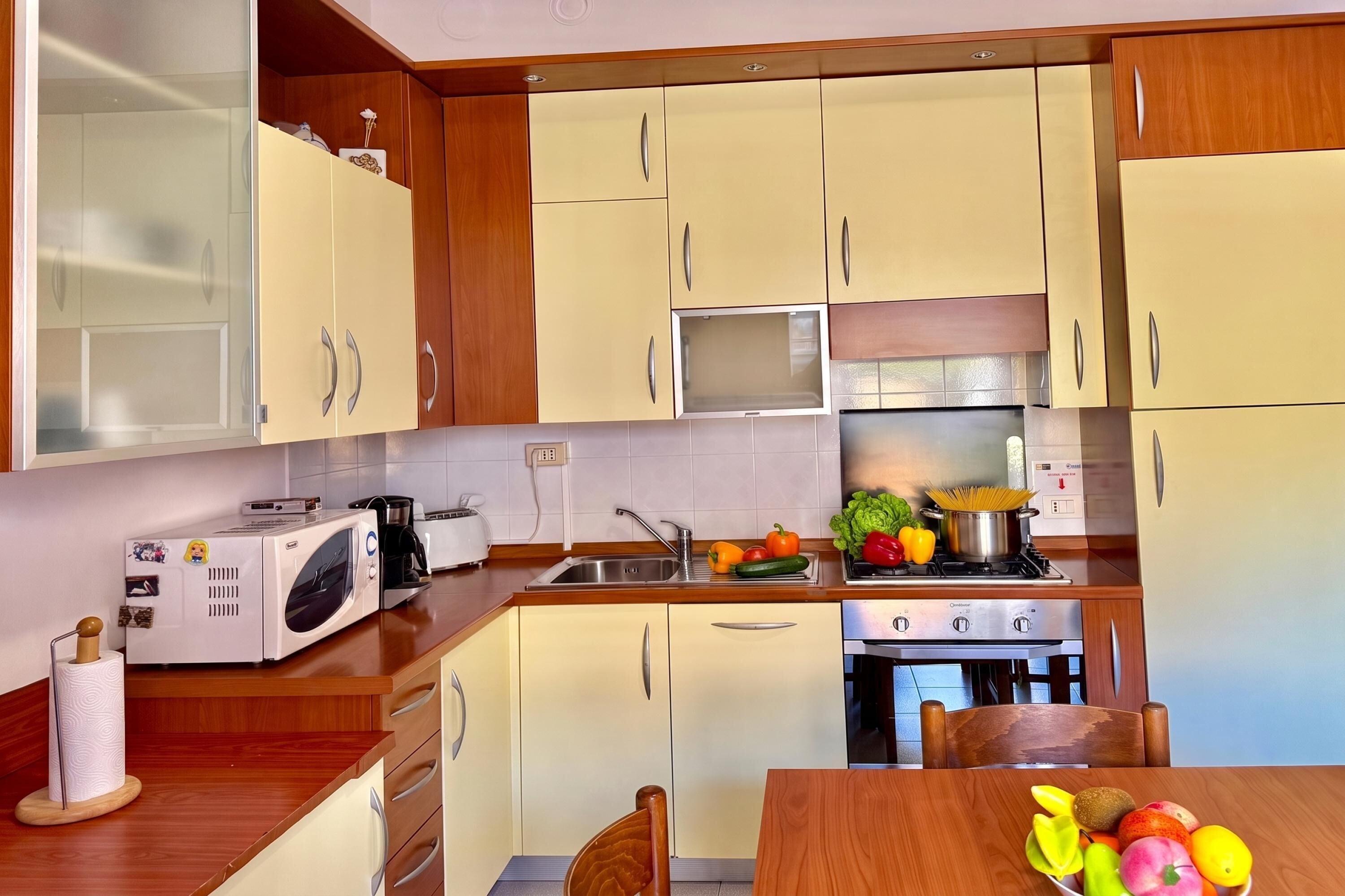 A kitchen with wooden cabinets, a microwave, a toaster, a sink, and a stove.