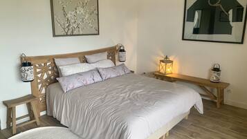 A bedroom with a wooden headboard, a large bed with white bedding, two bedside tables with lanterns, and a framed picture on the wall.