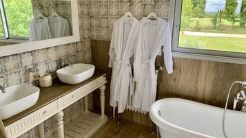 Une salle de bain avec un meuble-lavabo en bois, deux vasques, une baignoire et un grand miroir.