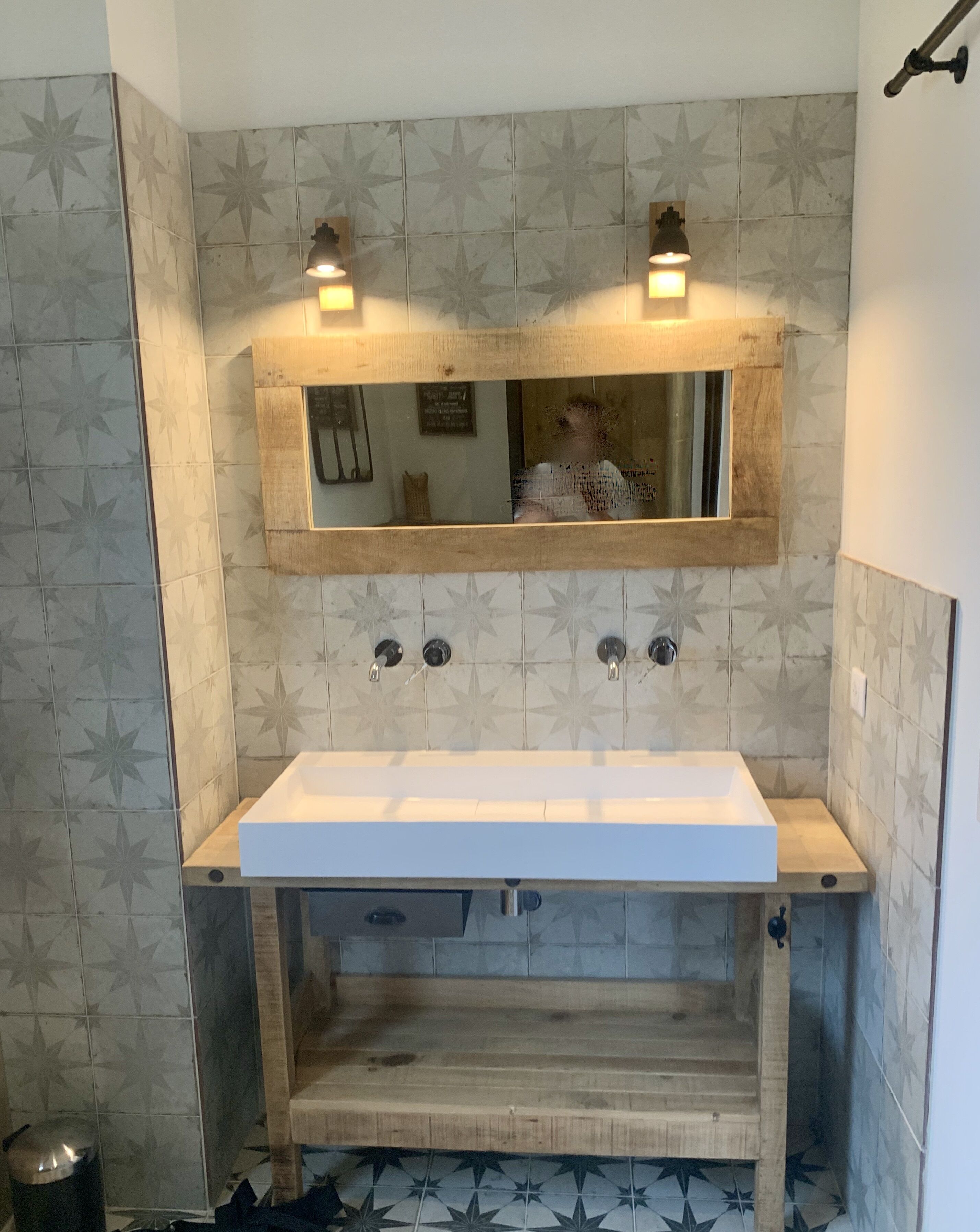 A bathroom with a rectangular sink, two wall-mounted lights, and a mirror above the sink.