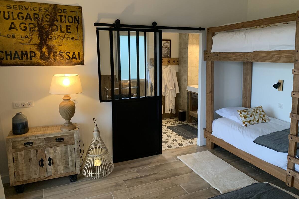 A room with a bunk bed, a wooden cabinet with a lamp, a hanging light fixture, and a sign on the wall.