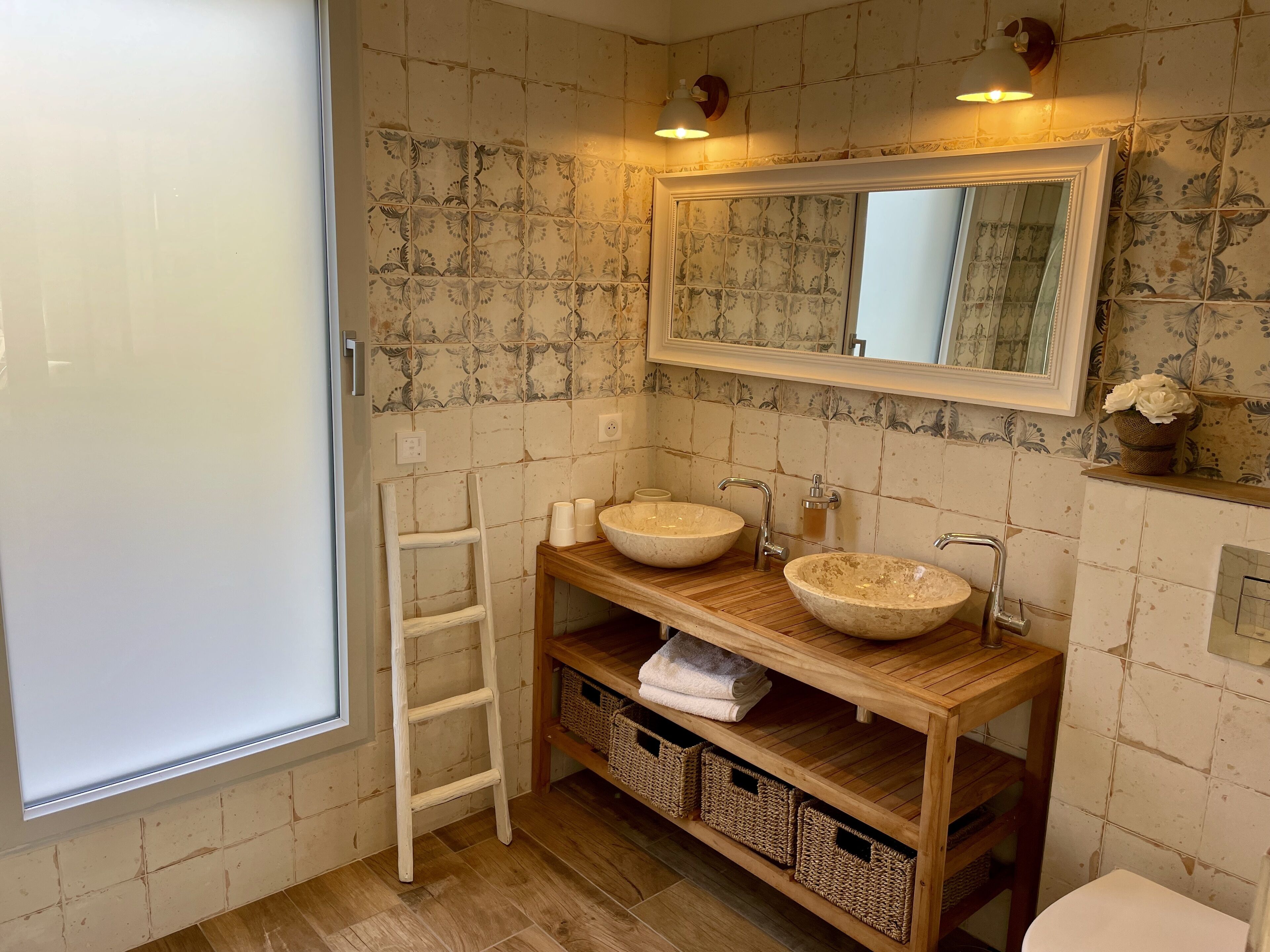 Un baño con dos lavamanos redondos, un tocador de madera, un espejo y una ventana.