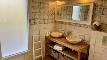 Un baño con dos lavamanos redondos, un tocador de madera, un espejo y una ventana.