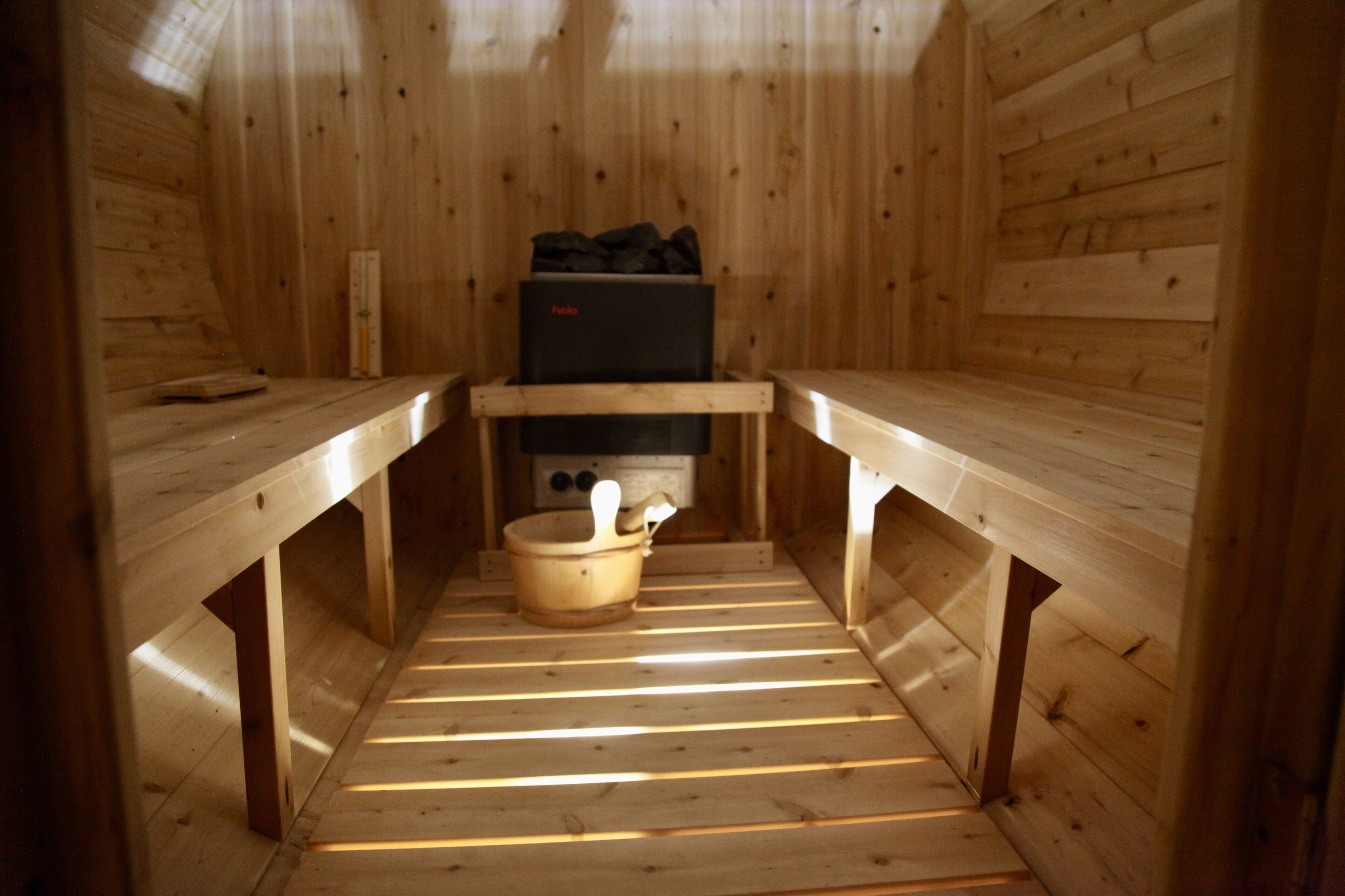 Una sauna con bancos de madera, un asiento en banco y piso de madera.