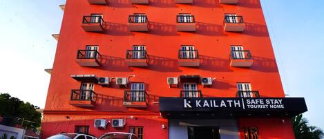 Un edificio rojo con varios balcones y un letrero que dice "KAILATH Safe Stay Tourist Home".