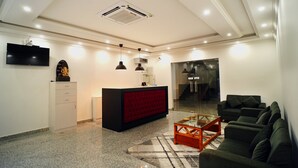 A modern living room with a red accent wall, a black sofa, a glass coffee table, and a flat-screen TV mounted on the wall. - Kailath Safe Stay Tourist Home (Tiruvalla)