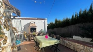 Un patio exterior con una mesa y sillas, un muro de piedra y un edificio con tejado de baldosas.