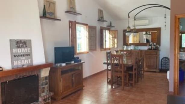 Una sala de estar amplia con chimenea, un comedor con muebles de madera y una cocina con horno integrado.