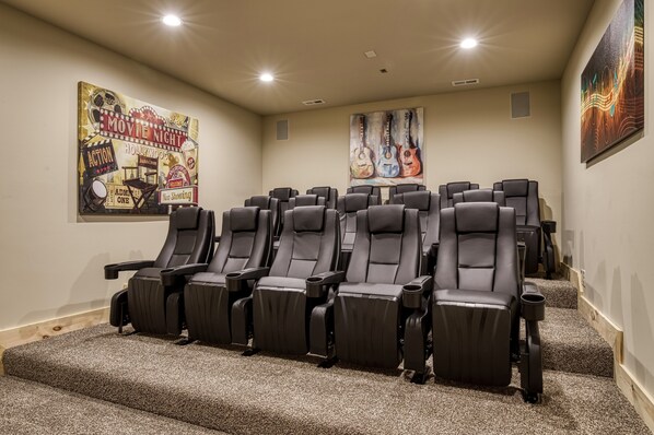 A home theater room with multiple reclining chairs, a carpeted floor, and a poster on the wall. - Top Notch Lodge- Private Indoor Pool, Theater, Stunning Mountain Views (Pigeon Forge)