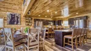 A spacious kitchen with wooden cabinetry, a central island, and modern appliances. - Top Notch Lodge- Private Indoor Pool, Theater, Stunning Mountain Views (Pigeon Forge)