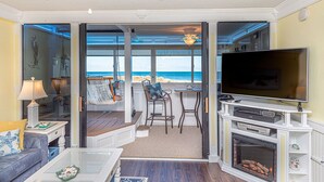 Un salon avec un téléviseur, une cheminée et une vue sur la plage.