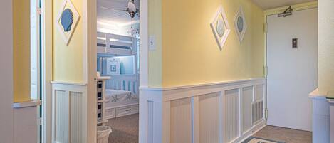 A hallway with a white wainscoting, a blue and white striped door, and a door with a white frame.