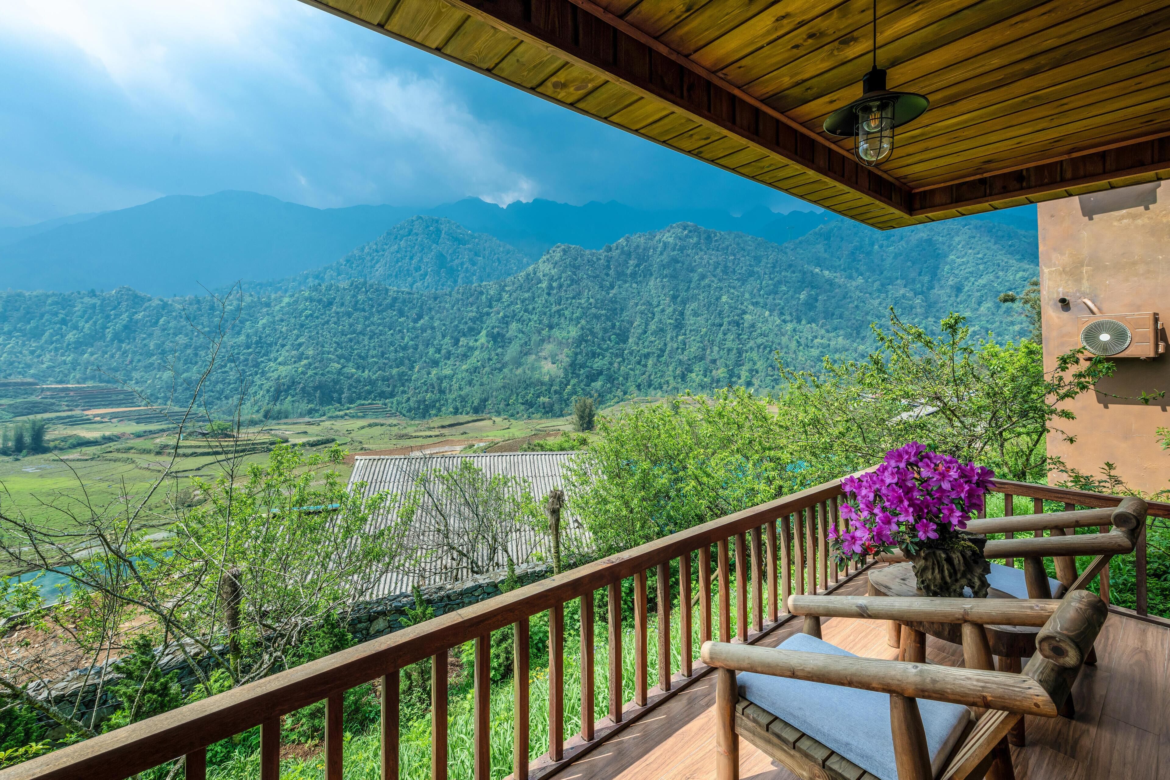 Una terraza de madera con vistas a montañas y un río.
