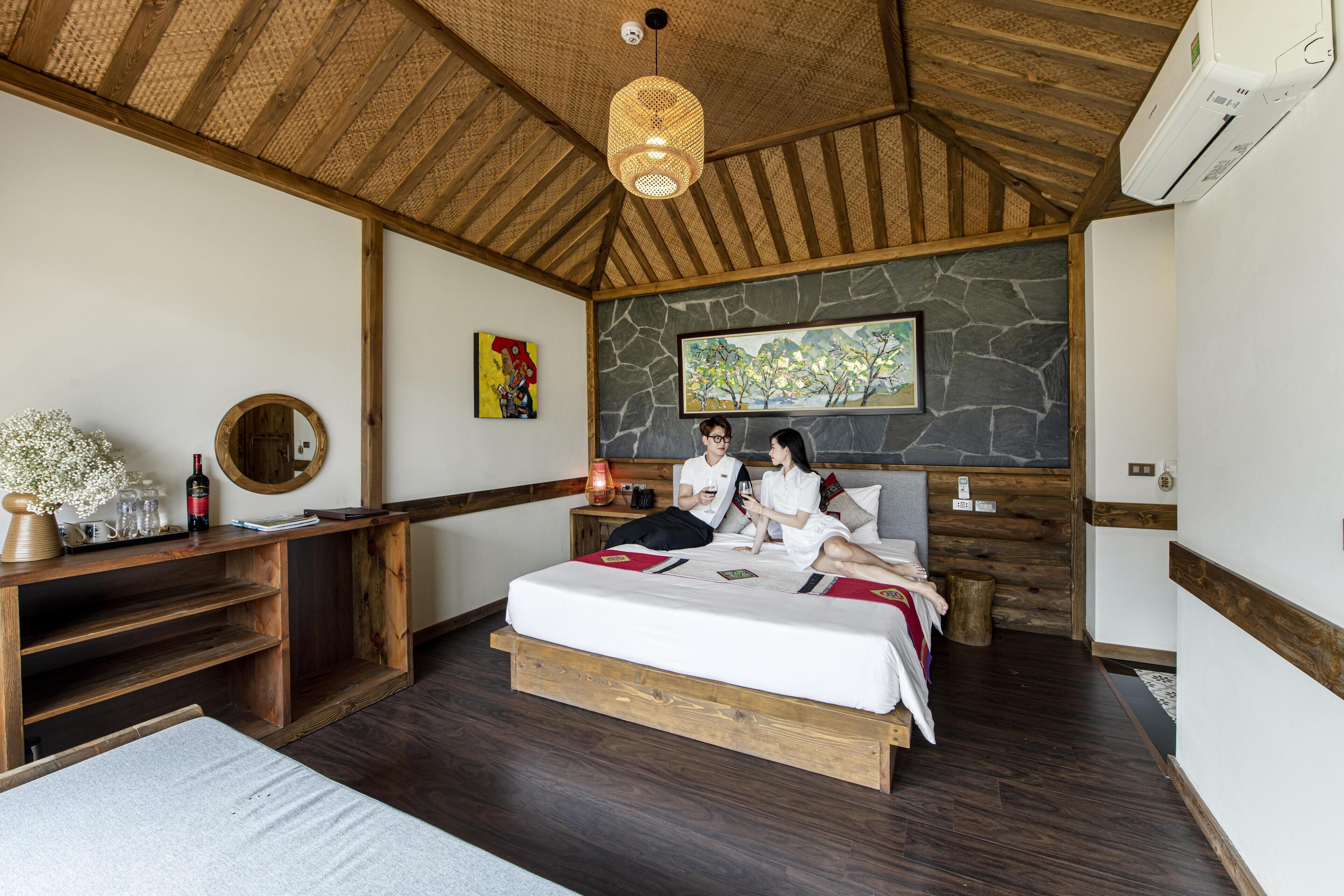 Un dormitorio con pared de piedra, techo de madera y cama con manta roja.