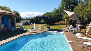 A swimming pool with lounge chairs and umbrellas, a covered patio, and a view of mountains in the background. - Peace and green charm (Salies-du-Salat)
