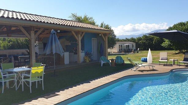 A covered patio area with outdoor furniture, a swimming pool, and a view of mountains in the background. - Peace and green charm (Salies-du-Salat)