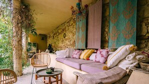 Une pièce chaleureuse avec un mur en pierre, un canapé confortable, une chaise en bois et une petite table ronde.