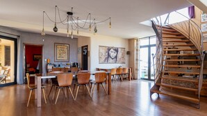Une salle à manger spacieuse avec un plancher en bois, un lustre moderne et un escalier en colimaçon.