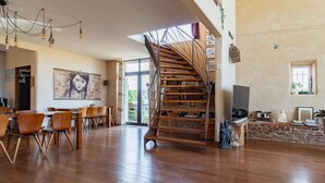 Un vaste espace de vie agrémenté d’un escalier en bois, d’une table à manger avec des chaises et d’une grande fenêtre qui laisse entrer la lumière naturelle.