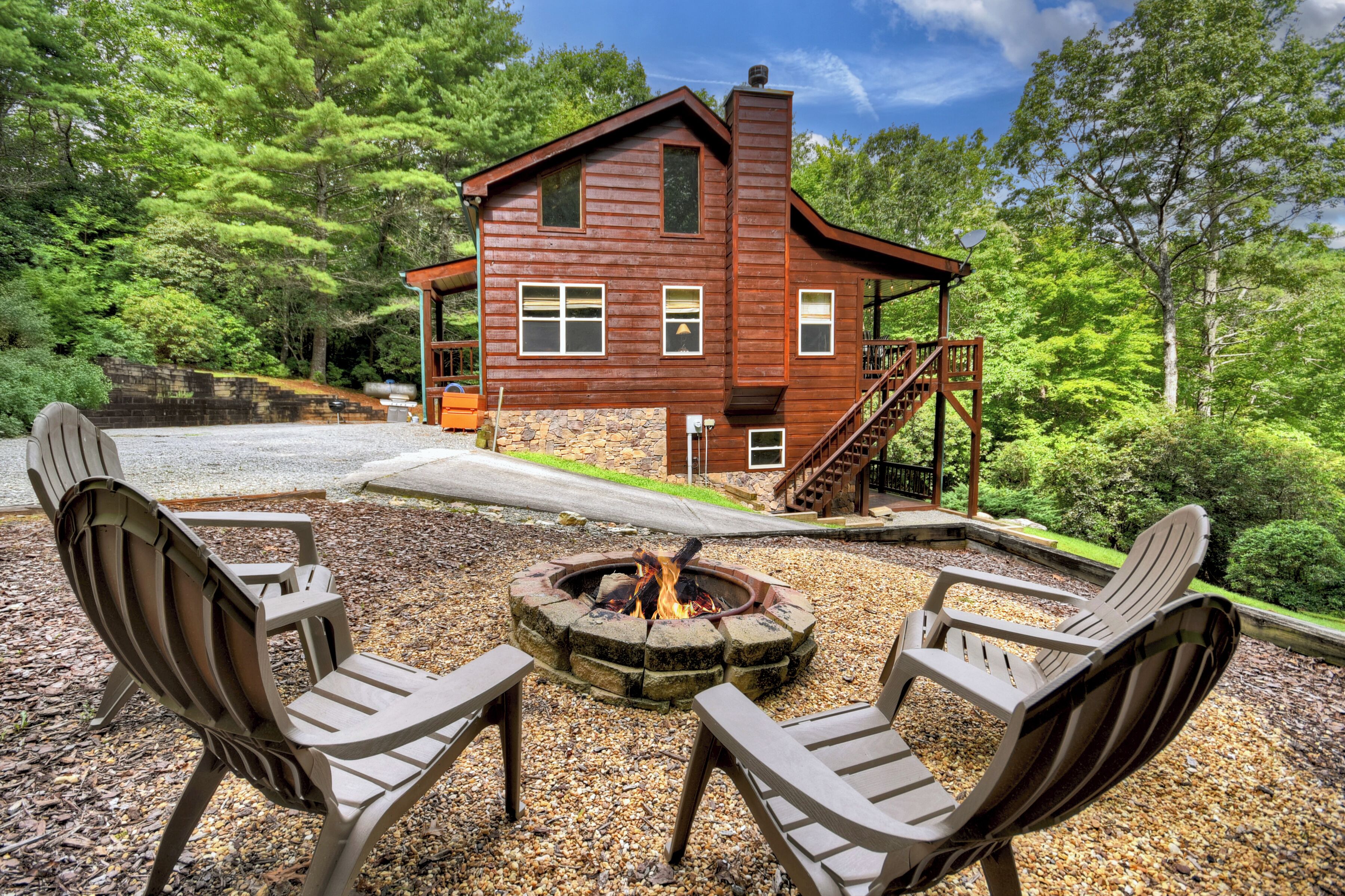 Une cabane en bois avec un foyer en pierre et des fauteuils Adirondack.