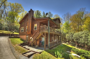 A wooden cabin with a balcony, a staircase, and a porch. - Unleash adventure at Four Ridges! This pet-friendly haven offers a hot tub, firepit, WiFi, and doorstep hiking for boundless exploration (Cherry Log)